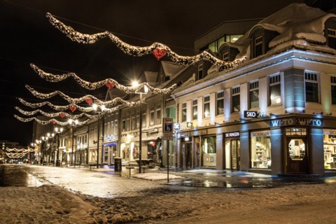 A view of the central street of Tromsø, Storgata, at polar night in winter, all lit up, with decorations for Christmas.