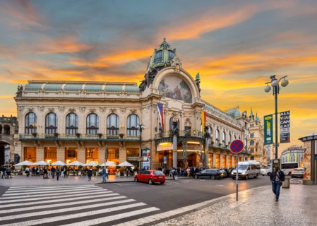 Sun sets in New Town Prague, Czech Republic as locals traverse the main street in front of the Prague Municipal House.