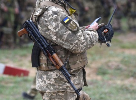 Soldier of Ukraine with assault rifle AK use smartphone. Ukrainian soldier with assault rifle AK.