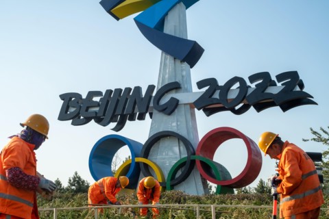 Urban ecological workers work in front of a huge emblem of Beijing 2022 Winter Olympics in Beijing, China. 14-Nov-2021