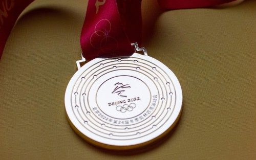 January 14, 2022, Beijing, China. Gold medal of the XXIV Olympic Winter Games on a yellow background.