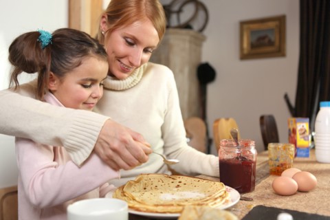 loving mother making crepes with little girl