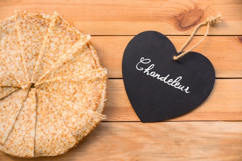 Top view of crepes (french pancakes), word chandeleur (meaning candlemas) written on a heart, rustic wood background