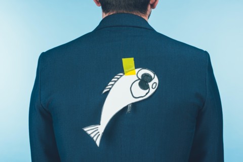 back view of businessman in suit with paper made fish on back, april fools day concept