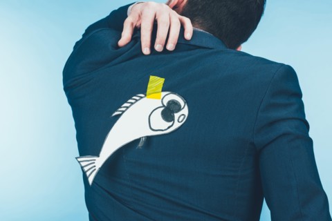 back view of businessman in suit with paper made fish on back, april fools day concept