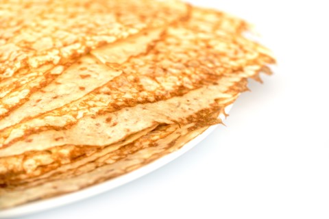 Close up on a stack of crepes (french pancakes) on a plate, white background