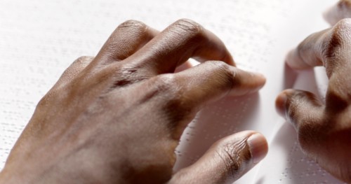 A black man is reading braille