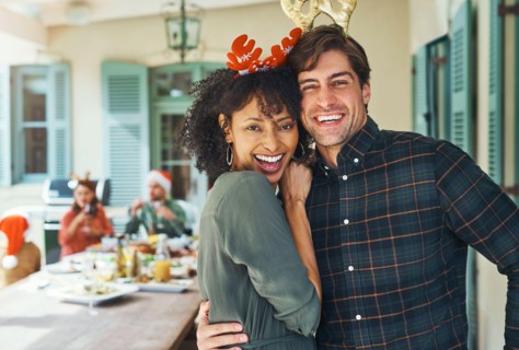 Spend your Christmas with the people you love. Portrait of a happy young couple celebrating Christmas together over lunch with friends and family in
