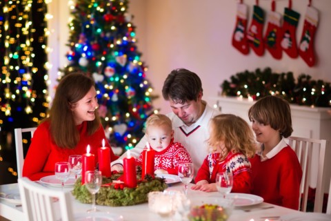 Big family with three children celebrating Christmas at home. Festive dinner at fireplace and Xmas tree. Parent and kids eating