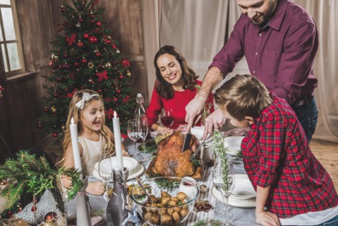 Happy family of four having roasted turkey for Christmas dinner