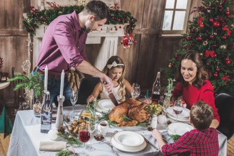 Happy family of four having roasted turkey for Christmas dinner