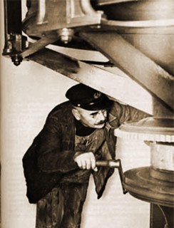 Adjusting the clockwork mechanism of a lighthouse lamp, a task that used to be regularly carried out before the automation of British lighthouses.