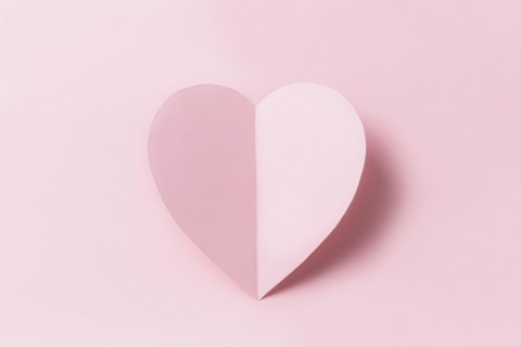 Love message or Saint Valentine Day conceptual flat lay. Top view on cut and curved paper pink heart with shadow on pink background. Minimalistic mockup for valentine card, invitation or greeting card