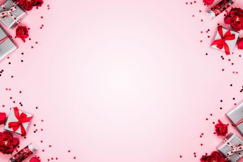Saint Valentine Day or Mothers day card template, greeting or invitation flat lay for wedding. Top view on pink background with paper gift boxes with red ribbons decorated with heart confetti, shapes