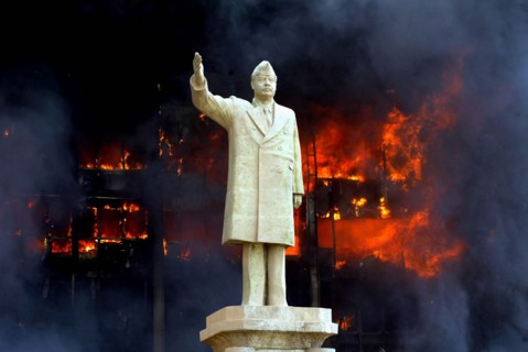 Iraq War April 2003 Baghdad American marines takeup postions in Eastern Baghdad Our Picture Shows Saddam s son Uday office in flames as his father s statue stands in front
