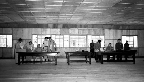 General William K. Harrison, Jr., seated at left, and North Korean General Nam Il, seated at right, sign armistice documents in Armistice Hall in Panmunjom, a no-man's-land between the Koreas. The 195...