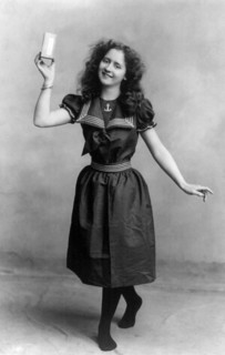 Young woman wearing turn-of-the-century bathing suit, posed holding unidentifiable product, 1901. By the end of the 19th century people were flocking to the oceanside beaches for popular seaside activ...