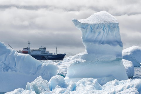 View between two snow peaks to a small cruise ship, Antarctic Peninsula, West Antarktika