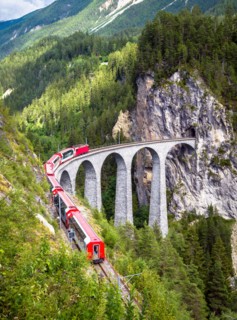 Rhaetian express moves on Landwasser Viaduct, Switzerland. This place is landmark of Swiss Alps. Vertical view of railroad bridge and red train, nice