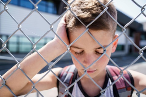 very sad boy bullying in school playground.