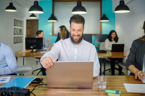 Cheerful man working on laptop in coworking space
