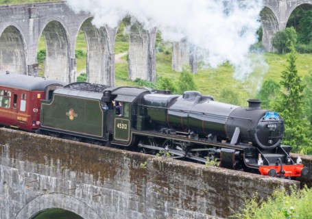 Glenfinnan,Inverness-shire,Scottish Highlands-July 21 2022:The train driver waves and lets off steam to onlookers,as the iconic train,shown in Harry P