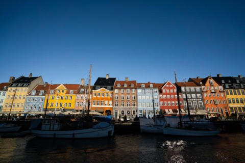 The colourful streets of Copenhagen, Denmark, along Nyhavn Quayside, on a sunny day with a blue sky.