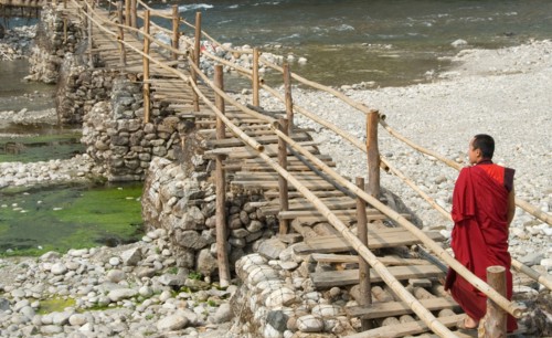 Monk walking to village from Punakha Dzong along temporary bamboo suspension bridge over Mo Chhu (Mother River), Bhutan