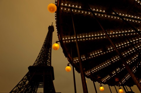 Evening at the Eiffel tour with carousel turning at the basement; Paris, France