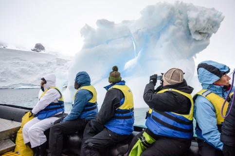 ANTARCTICA - A group of tourists cruise on the side of an inflatable boat past an a small iceberg in Curtis Bay, Antarctica.