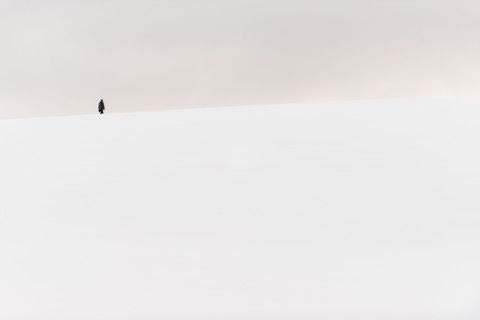 ANTARCTICA - A person hikes to the top of a small snow-covered hill in Hughes Bay on the western coast of the Antarctic Peninsula.