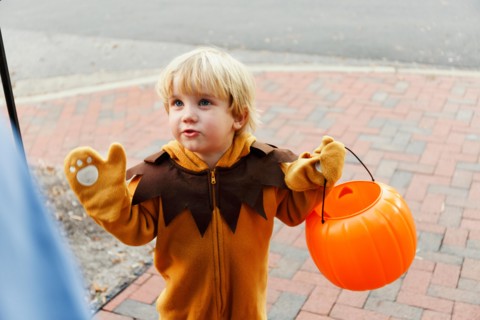 Caucasian boy in lion costume trick or treating on Halloween