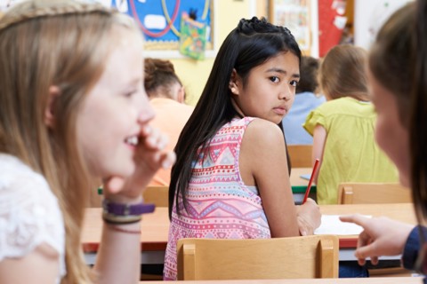 Unhappy Girl Being Gossiped About By School Friends In Classroom