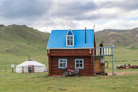 Mongolian man on the terrace of his wooden house. Tariat district, North Hangay province, Mongolia.