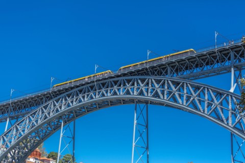 View of the metallic bridge of D. Maria Pia, built by Gustave Eiffel, with yellow subway wagon, in Porto, Portugal