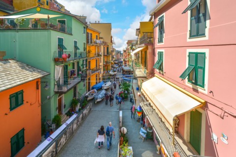 Tourists walk towards the sea at the colorful fishing village of Manarola, Italy, part of the Cinque Terre on the Ligurian Coast.