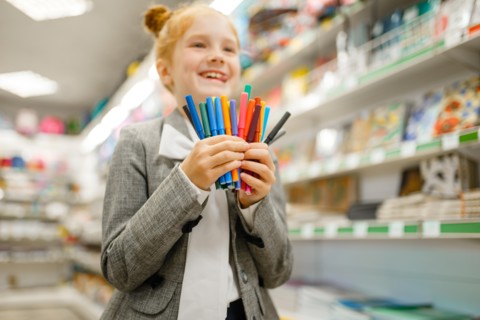 School girl holds markers, stationery store