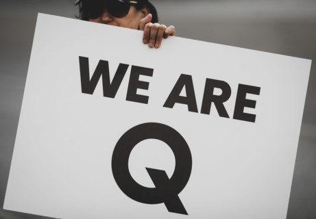 Bucharest, Romania - August 10, 2020: A woman takes part at a protest and displays a Qanon message on a cardboard.