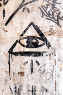 Illuminati logo painted on the wall. "All seeing eye" of God in sacred geometry triangle. Masonry and Illuminati symbol in triangle with light ray.