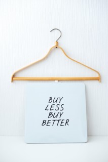 Sustainable consumption and production. Circular economy, Sustainable fashion concept with wooden clothes hangers and text Buy less, buy better