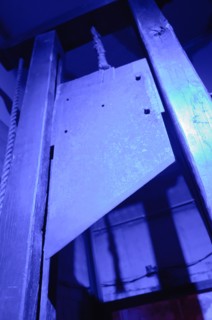 Blade of a guillotine lit with blue light