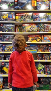 little boy admiring a plaything-shelf with LEGO packings
