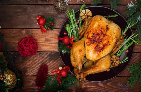 Baked turkey or chicken. The Christmas table is served with a turkey, decorated with bright tinsel and candles. Fried chicken, table. Christmas dinner