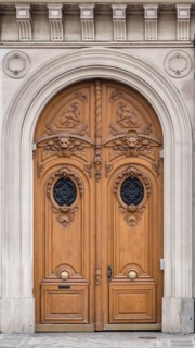 Antique inlaid wooden door with carved stone structure in an ancient palace in Paris.