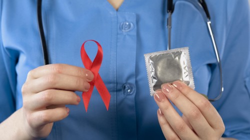 Doctor warning about AIDS disease showing red ribbon and condom, health campaign, stock footage