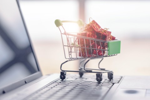 Gift boxes in a shopping cart on a laptop keyboard.