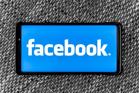 Facebook page on the smartphone on fabric background. Facebook is very well know social networking service founded in 2004 by Mark Zuckerberg