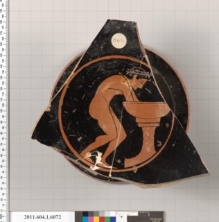 Terracotta fragment of a kylix (drinking cup) 510–500 B.C. Greek, Attic Interior, wreathed youth washing his hands in a laver; part of an inscription, [H]O PAIS [KALOS[. Terracotta fragment of a kylix...