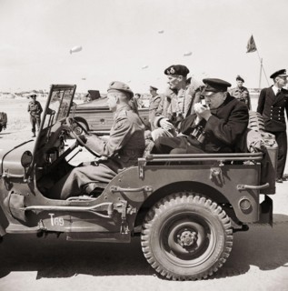 Winston Churchill lights a cigar in the back of a jeep while touring the Normandy beaches with General Mongomery, 12 June 1944.