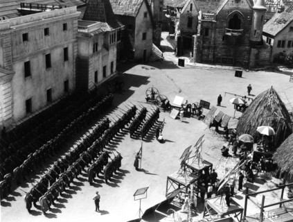 On Set candid filming Parade of German Soldiers on Universal Studios Lot with part of Paris set from Lon Chaney's Hunchback of Notre Dame (1923) at top right and Native Huts from The Invisible Ray (19...